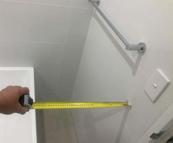 Image of hand holding a tape measure between sink and light switch