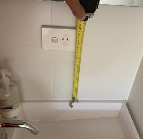 Image of tape measure showing the distance between a power point and a sink 